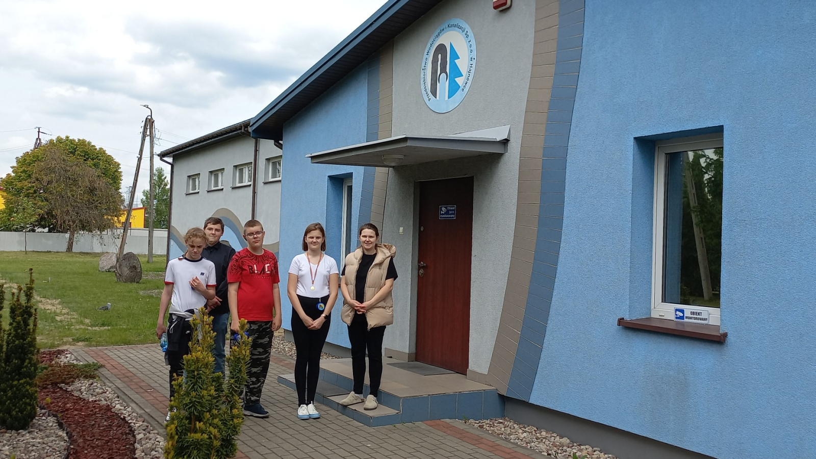 Uczniowie pozują do zdjęcia przed budynkiem stacji uzdatniania wody