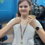 Uczennica pozuje do zdjęcia z kubkiem z hajnowską kranówką