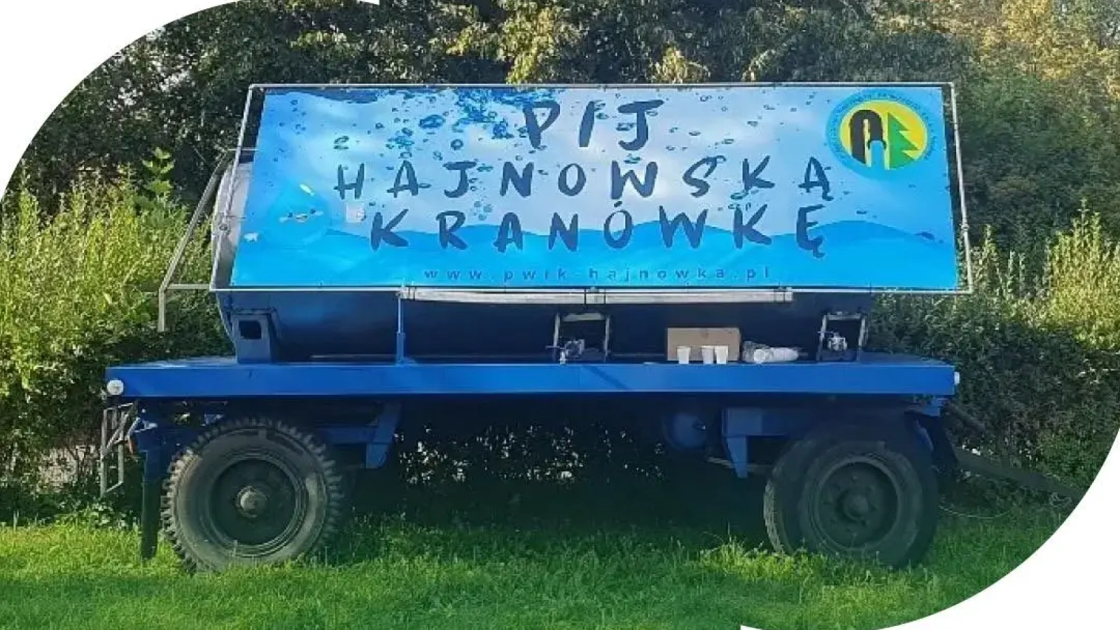 Zdjęcie cysterny z hajnowską kranówką, u dołu napis: "pijemy na Duchu hajnowską kranówkę"